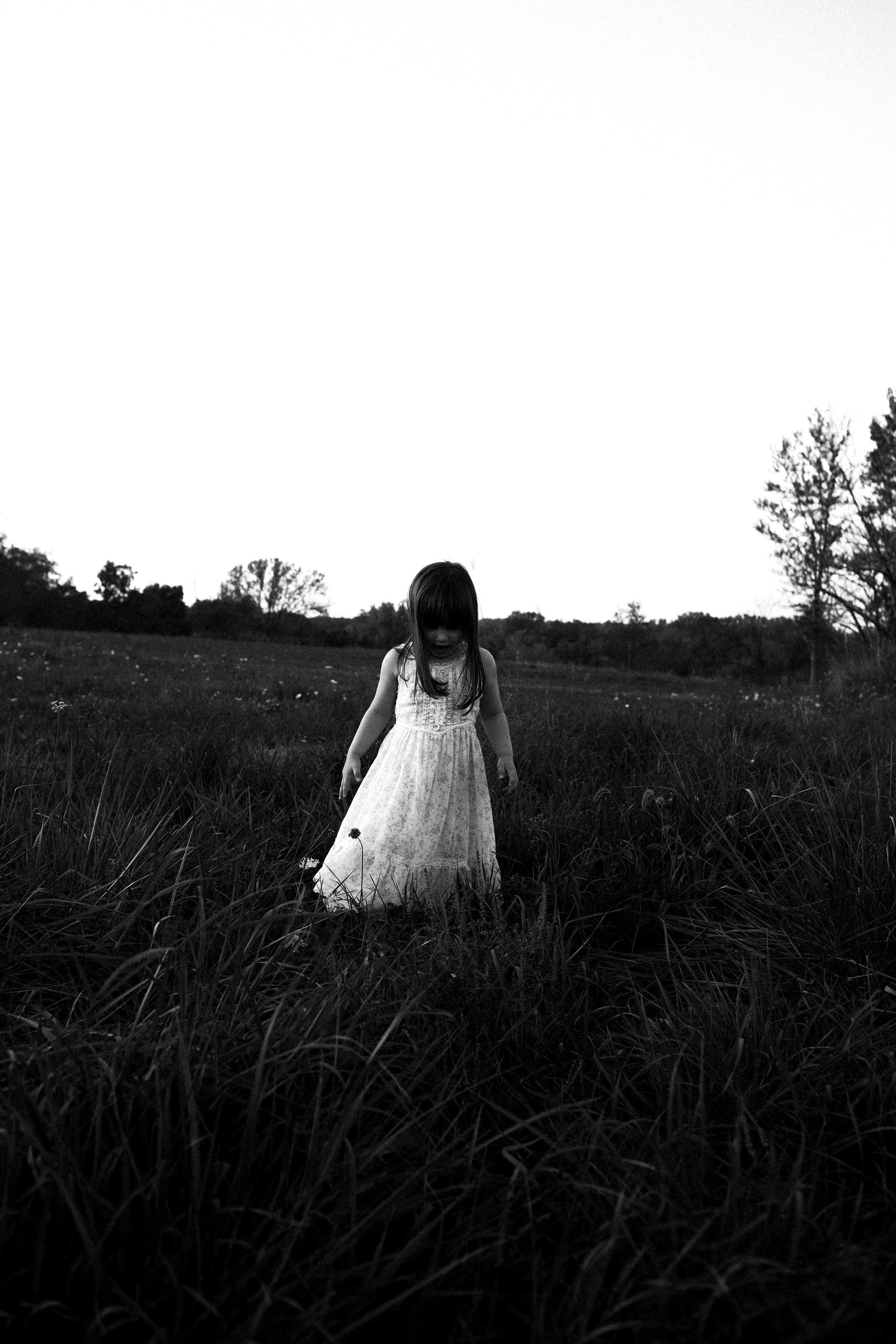 Children and lifestyle photography black and white of girl in vintage dress in field