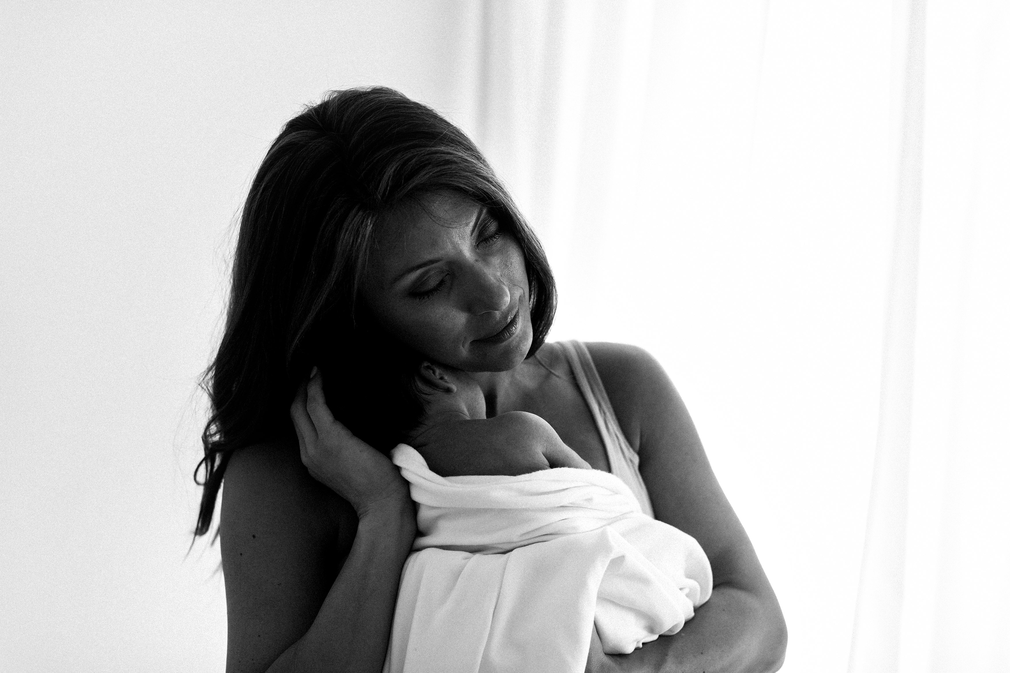New mom holding baby in natural light studio photo taken by Elle Baker Photography Chicago newborn photographer