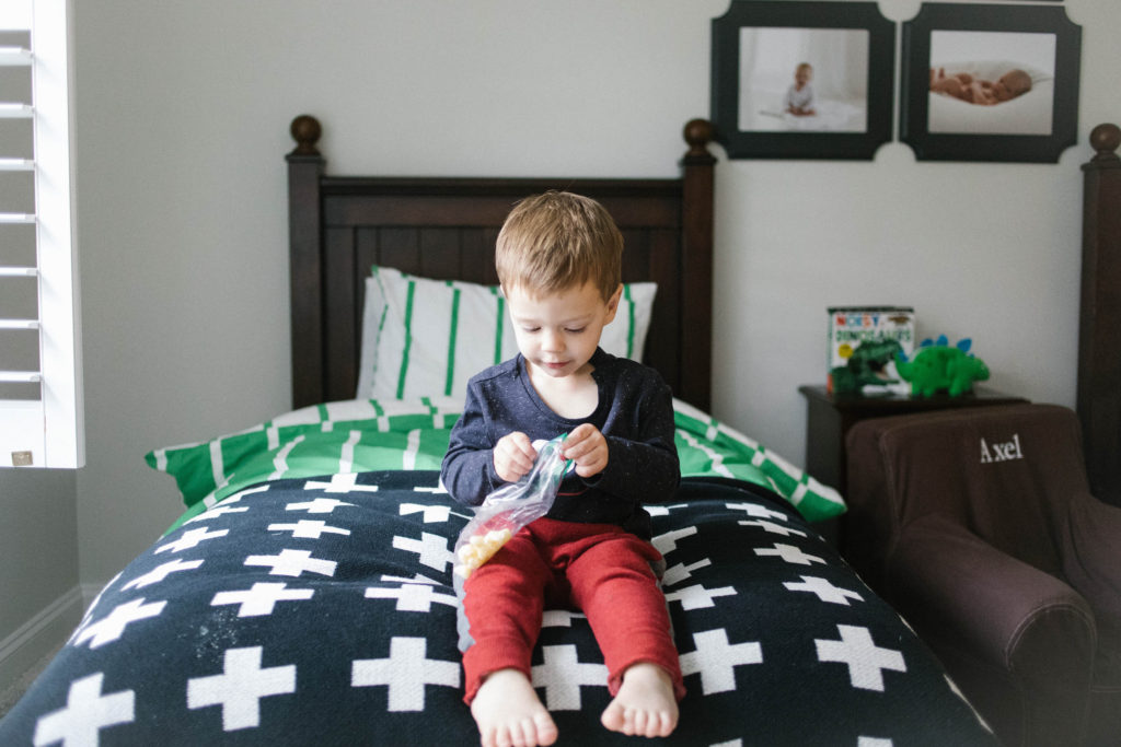 Family time in Lisle IL | Chicago family and lifestyle photographer captures boy eating cheese puffs on bed