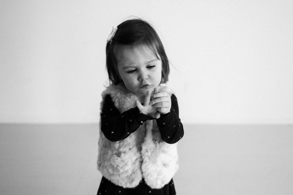 Six Month Milestone Sessions in Chicago photography studio.  Image of a little girl counting on her fingers during 2 year birthday session.