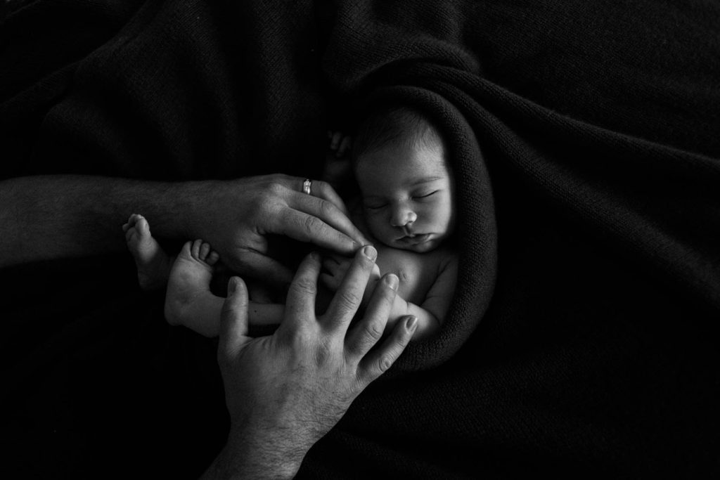 Homer Glen, IL newborn photography studio, Photo by Elle Baker Photography, black and white image of newborn with dad's hands
