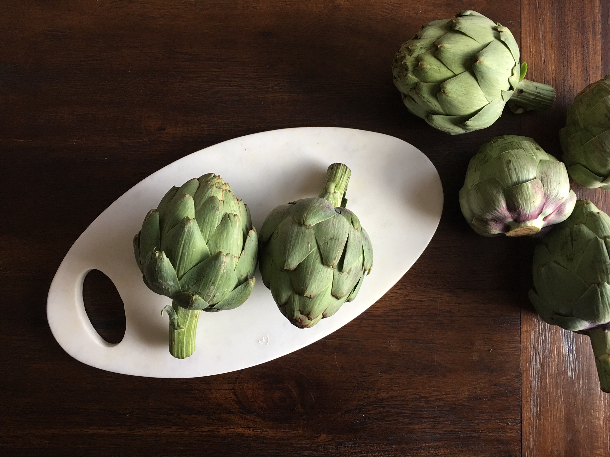 Stuffed Artichoke Recipe, Elle Baker Photography, green artichokes on white marble plate