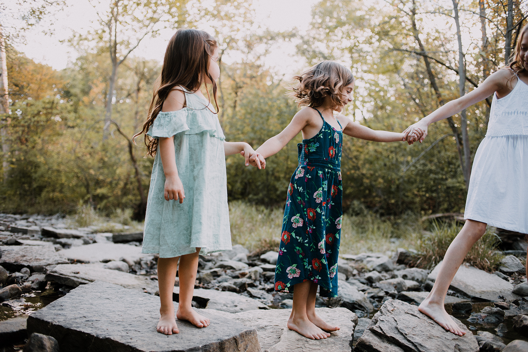Natural and candid family photography, photo by Elle Baker Photography, three sisters walking in river bed