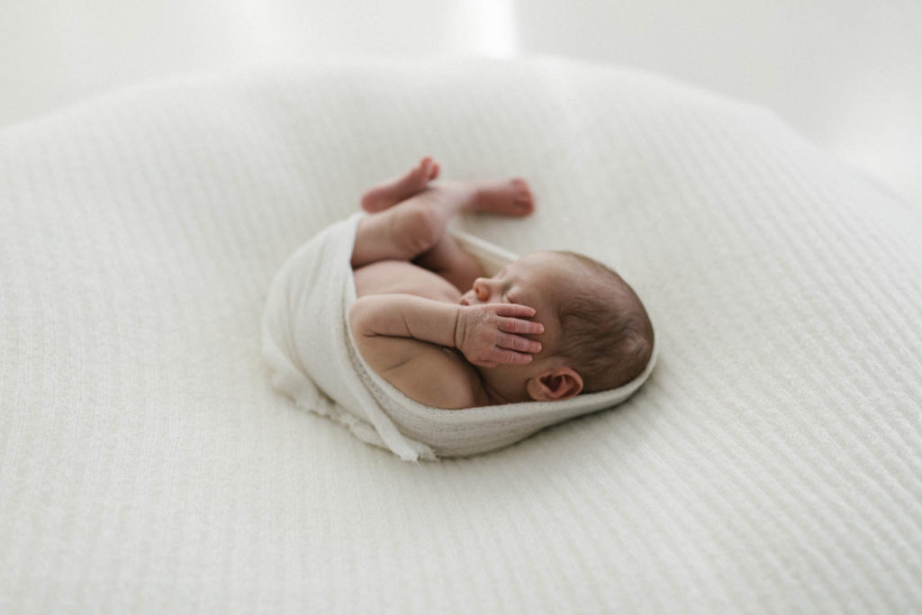 newborn laying on large white bean bag in a natural light studio in Chicago
