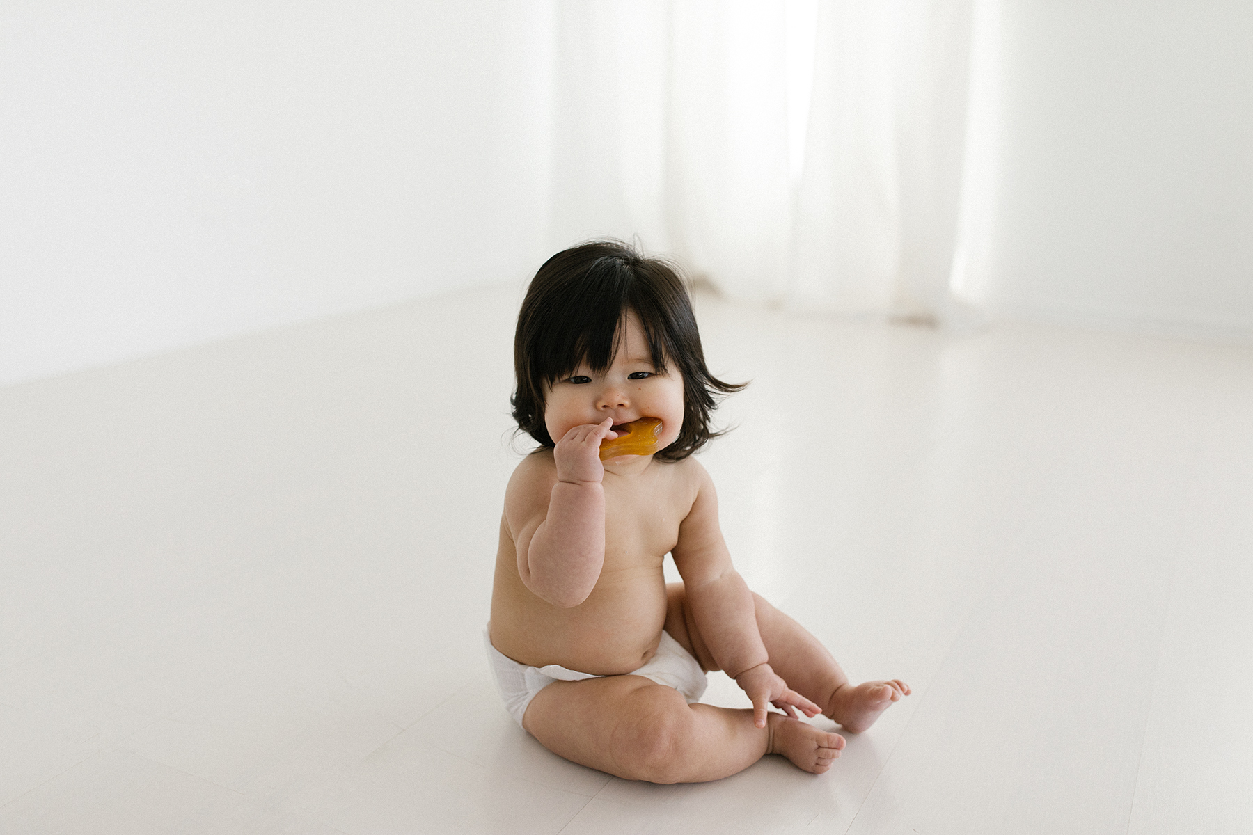 Little girl with dark hair chewing natural teether
