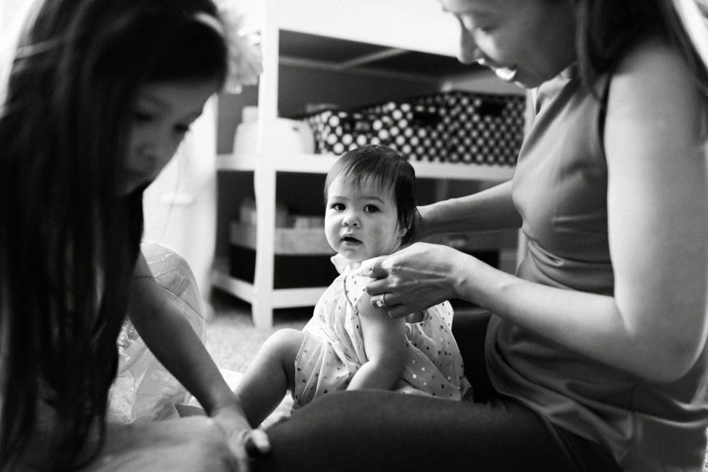 black and white image of mom getting baby girl dressed 