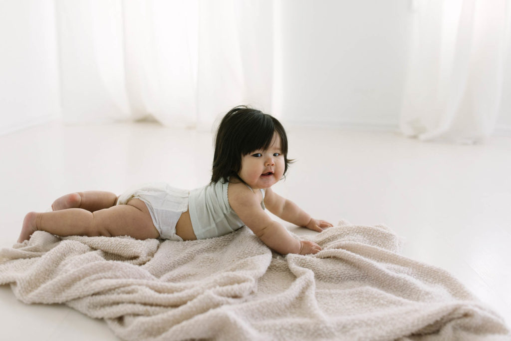 baby laying on tummy in a white and neutral studio 