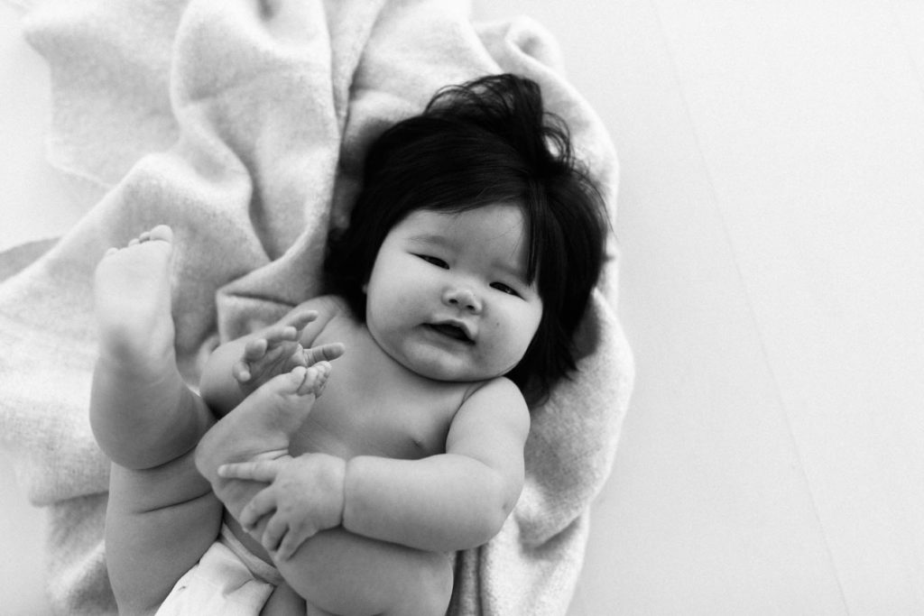 black and white image of a baby holding her toes in a diaper 
