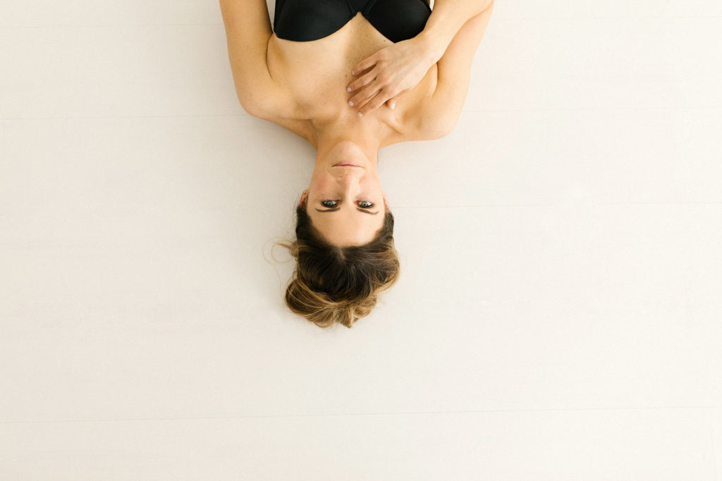 Boudoir Portrait Photographer in Homer Glen, Laurie Baker captures a gorgeous portrait of a woman with her hair up in a bun, gracefully laying on the floor 