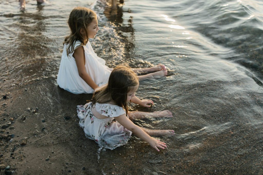 Laurie Baker captures natural photos of two girls playing in the sand during a sunset session 