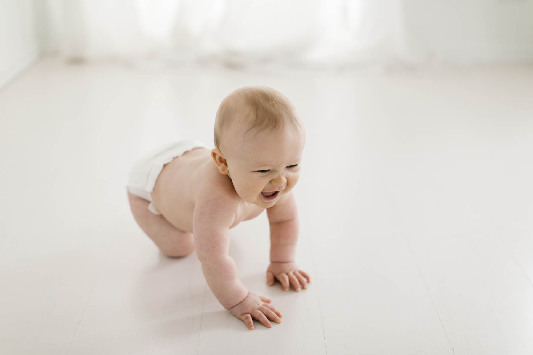 baby boy crawling on floor and laughing