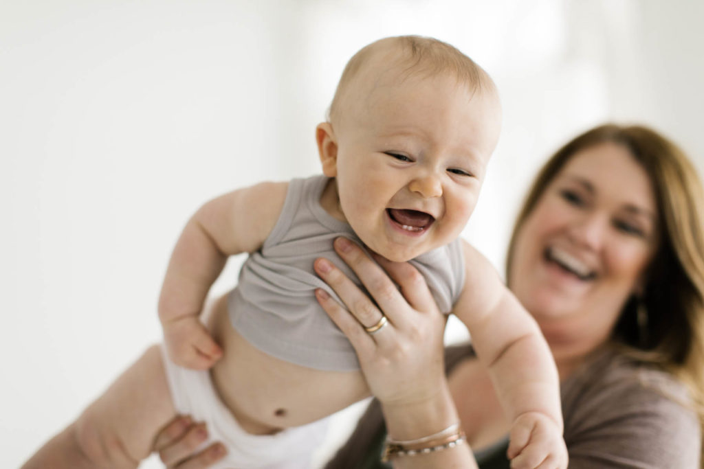 mom playing airplane with her baby boy during six month photo shoot