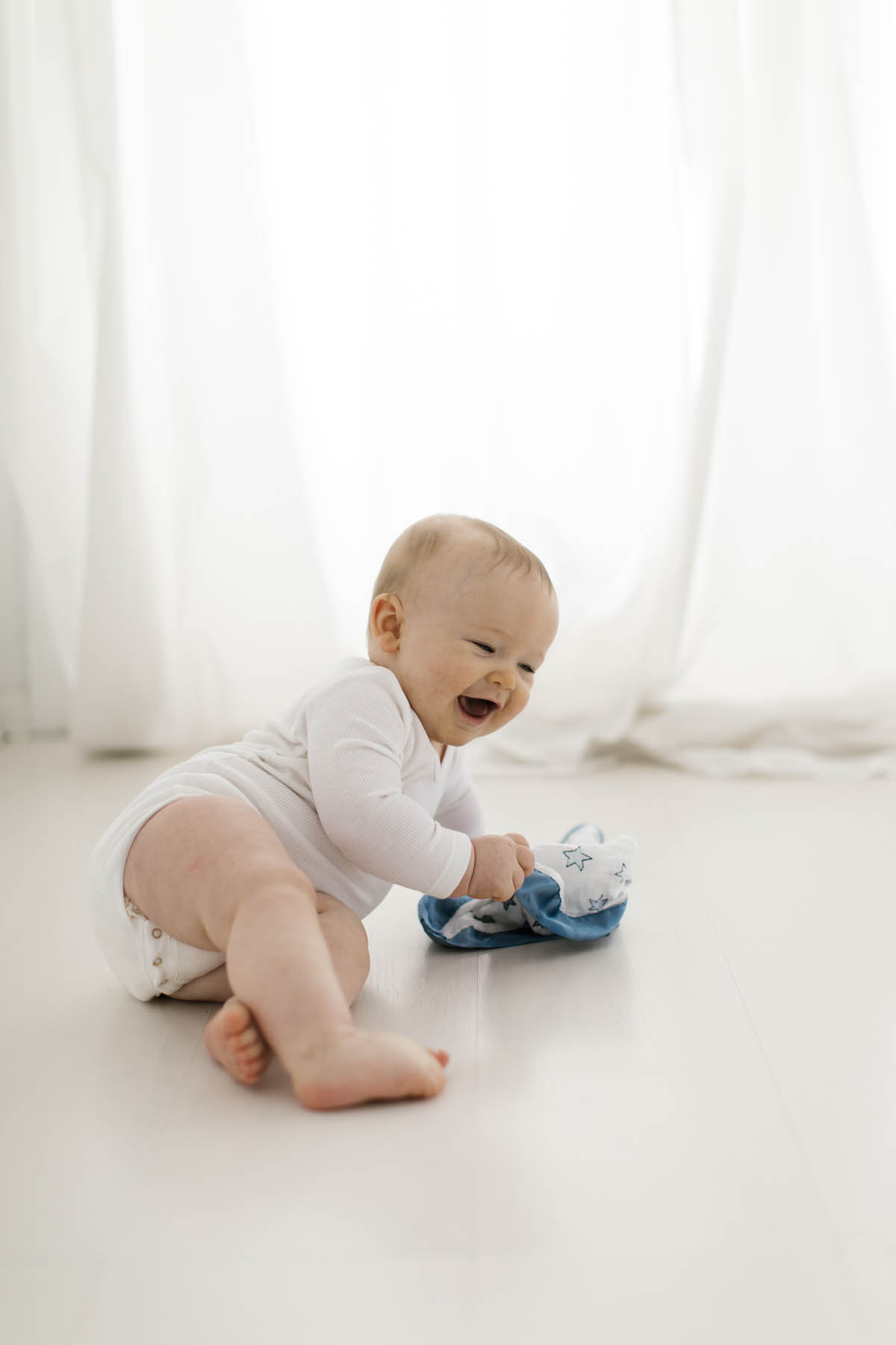 Elle Baker Photography captures baby boy laughing and holding his blanket