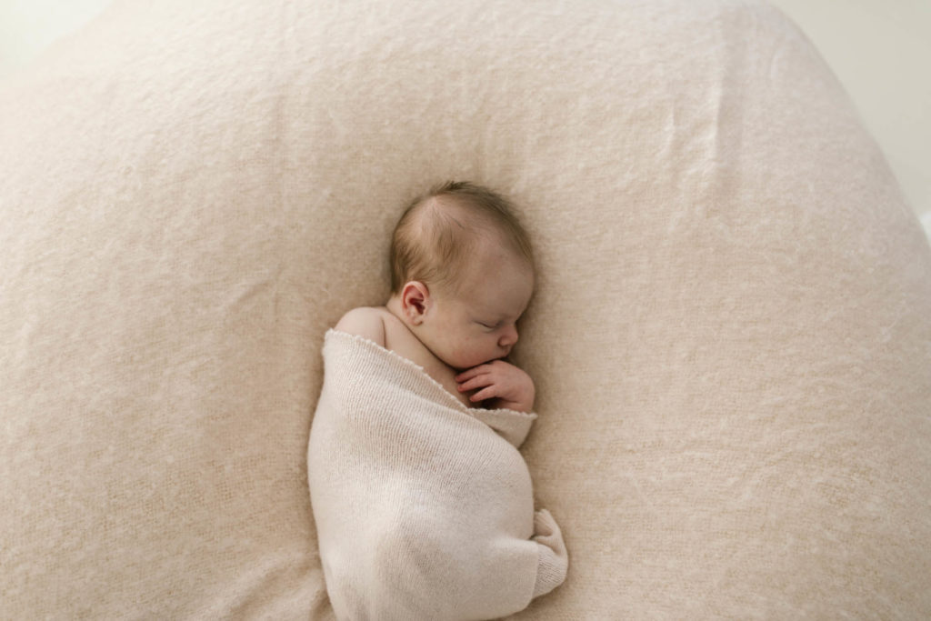 newborn infant laying on a blush colored blanket during newborn mini session 