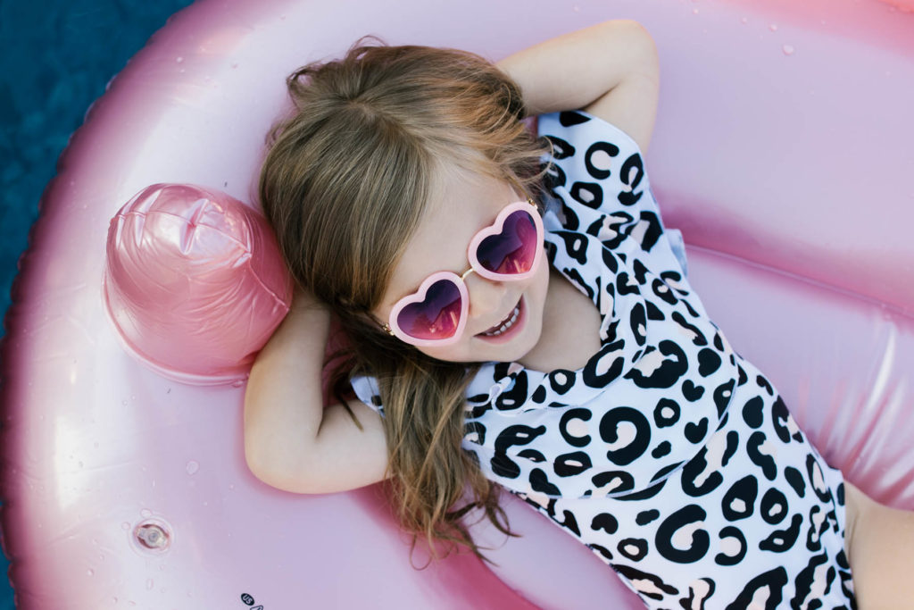 little girl with heart sunglasses on during pool photo session 