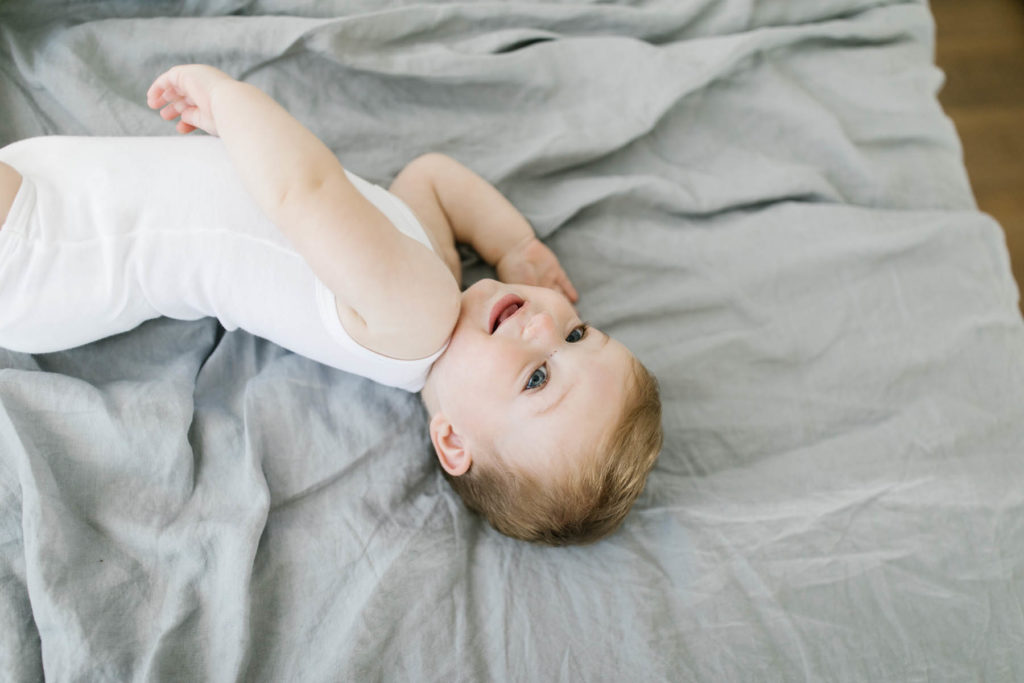 baby boy rolling on a bed during first birthday photo shoot 