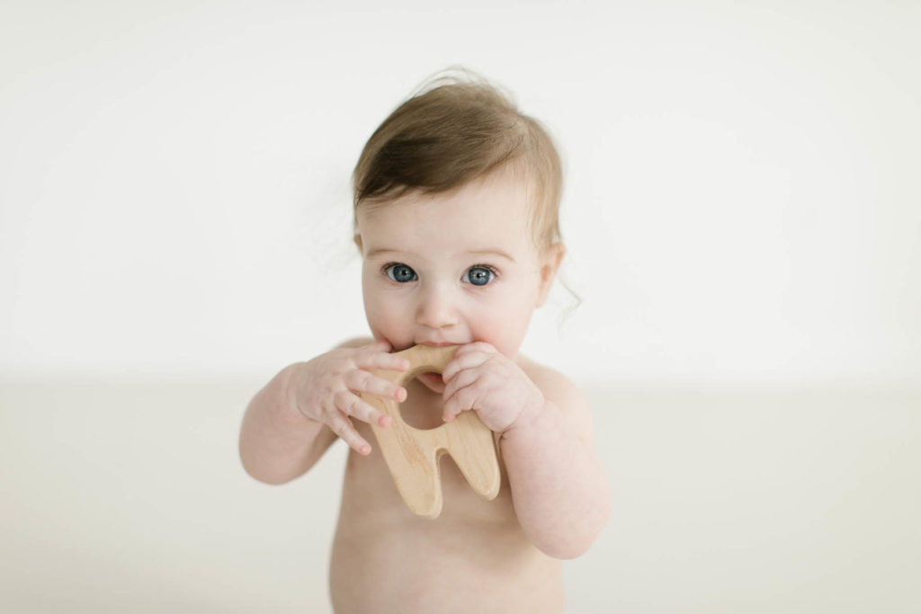 baby chews on a tooth teether toy 