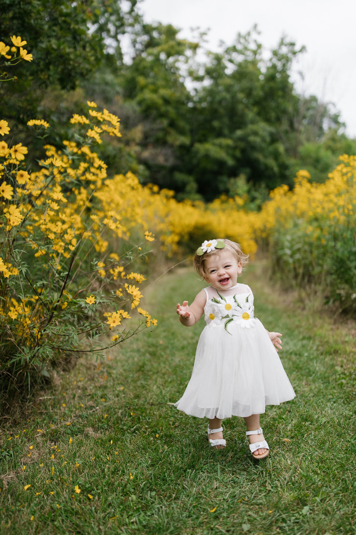little girl toddling through field of yellow flowers 