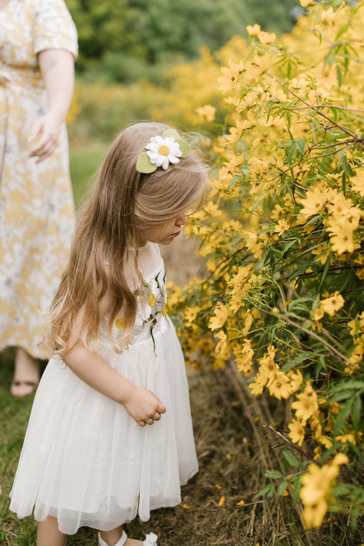 little girl with hair bow smelling flowers 