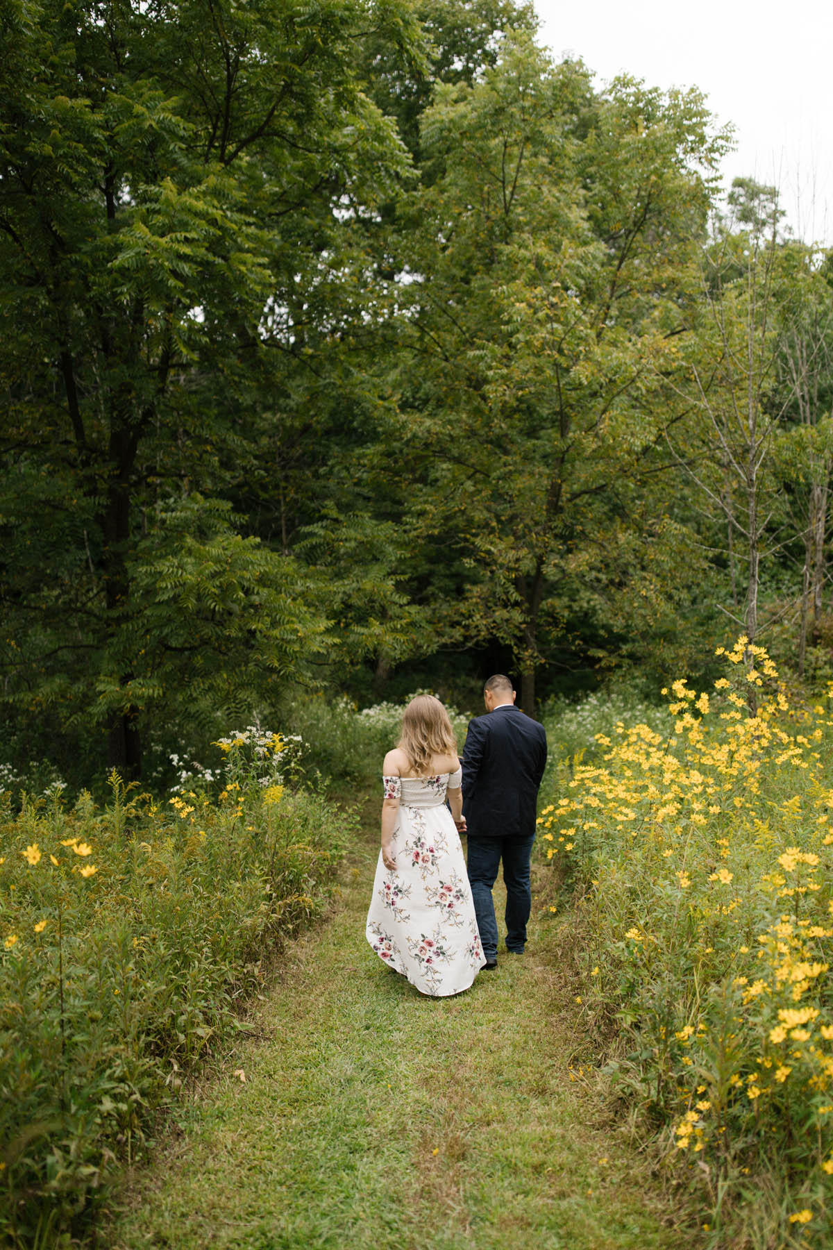 couple walking in a field during engagement photo shoot 