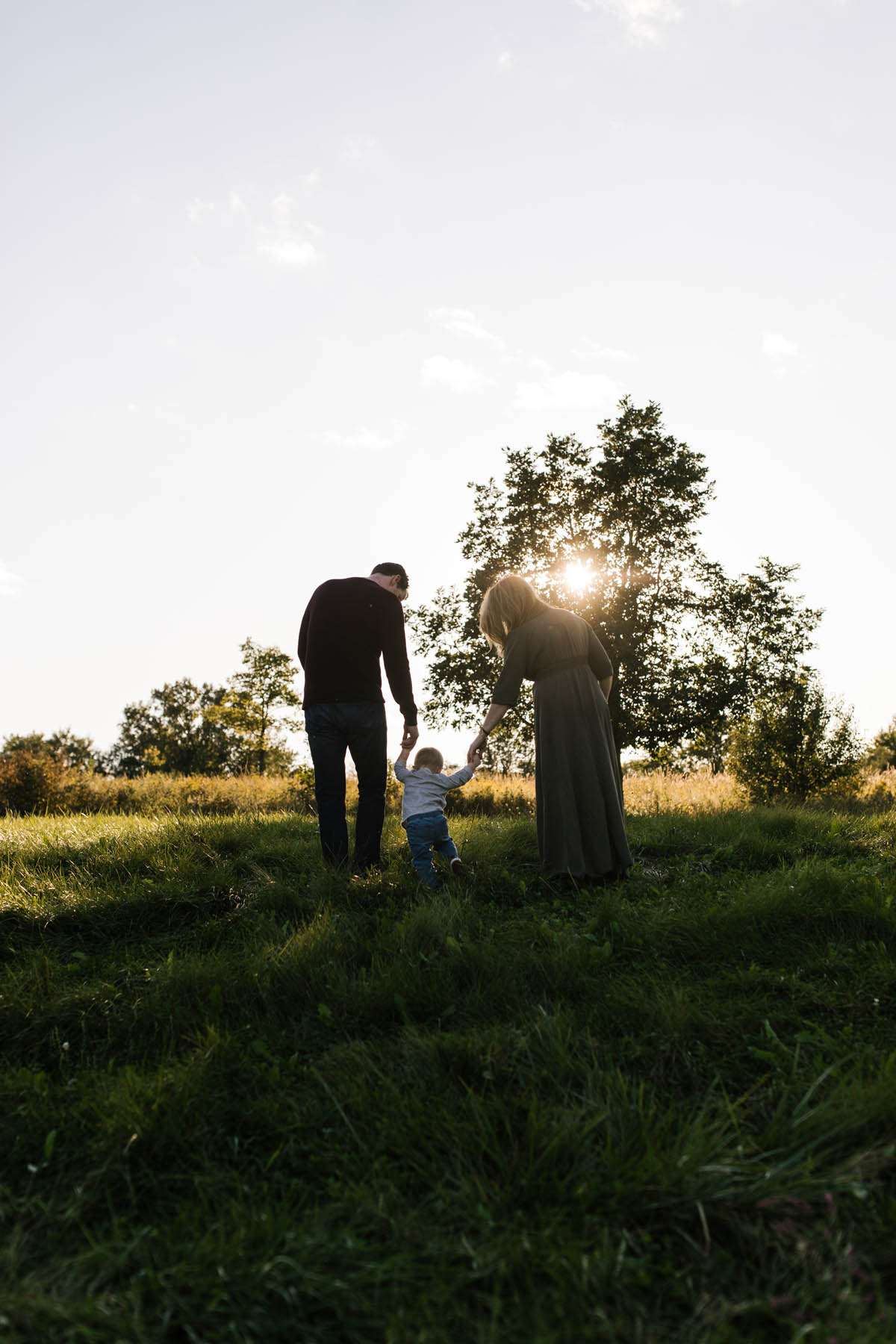 family of three walking into the sunset during family mini session 