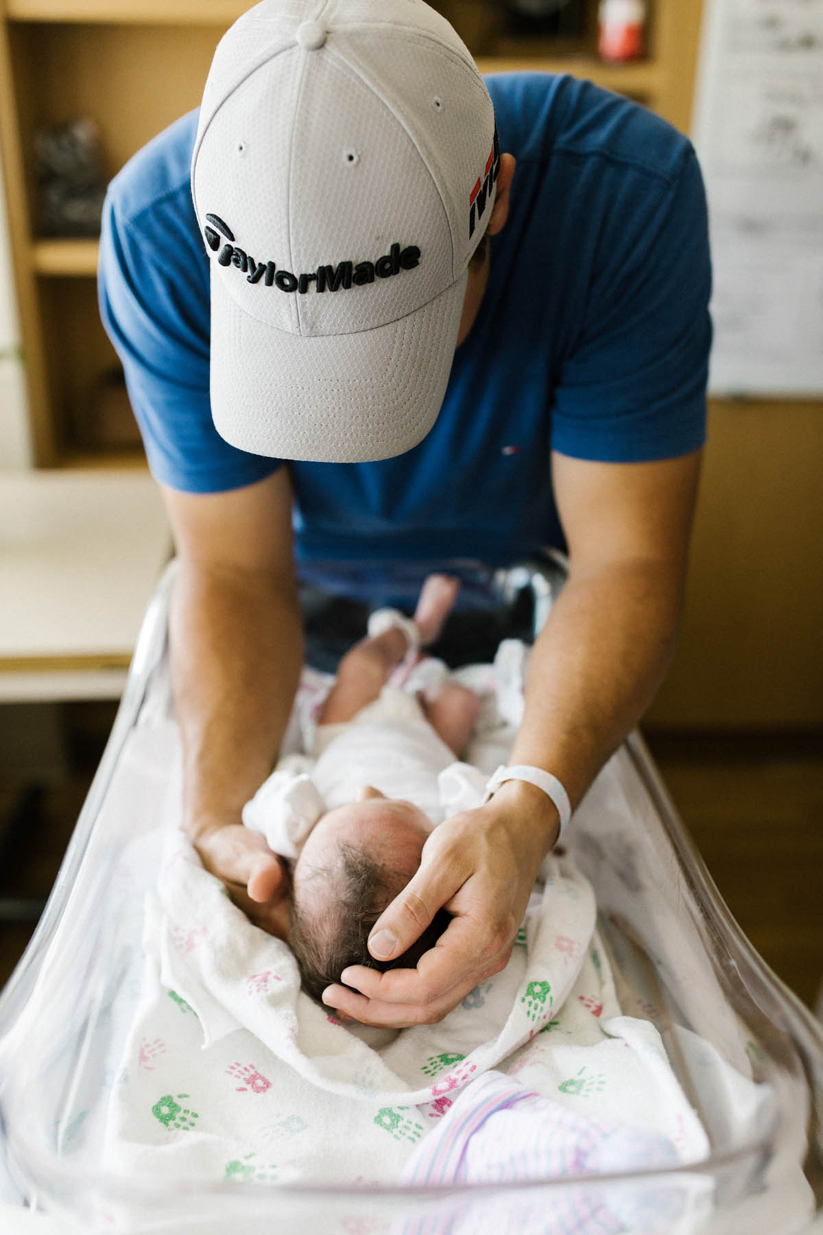 fresh 48 hospital session dad in baseball cap holding his baby boy for the first time