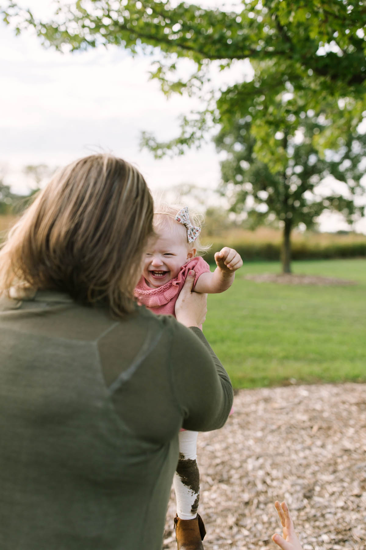 little girl laughs with tights and dress covered in mud during New Lenox family session 