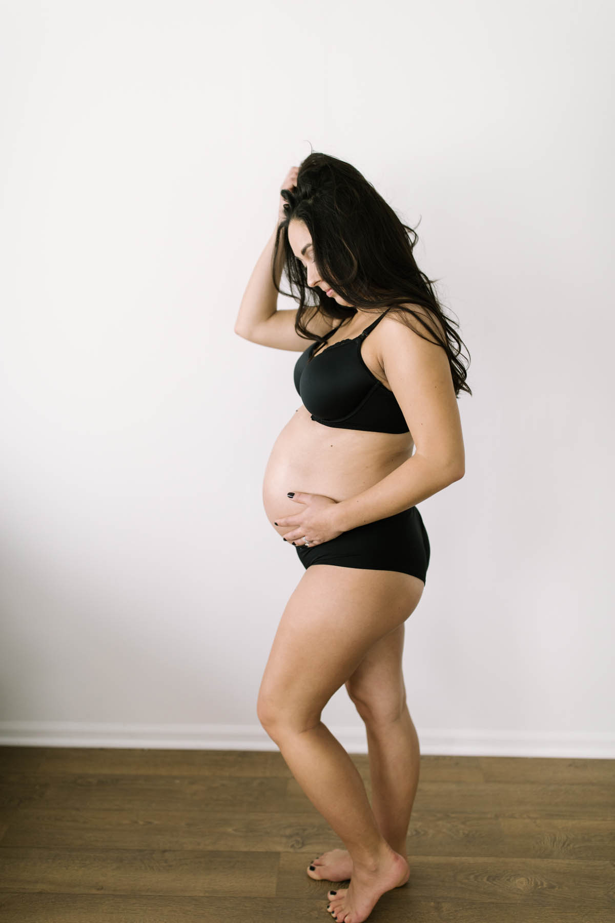 woman in a black bra set during her maternity photo session 