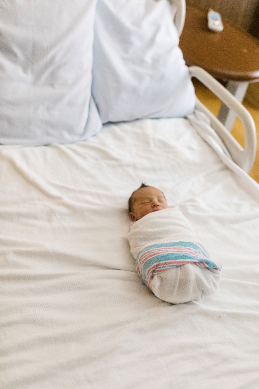 newborn wrapped in a blue and pink striped hospital blanket 