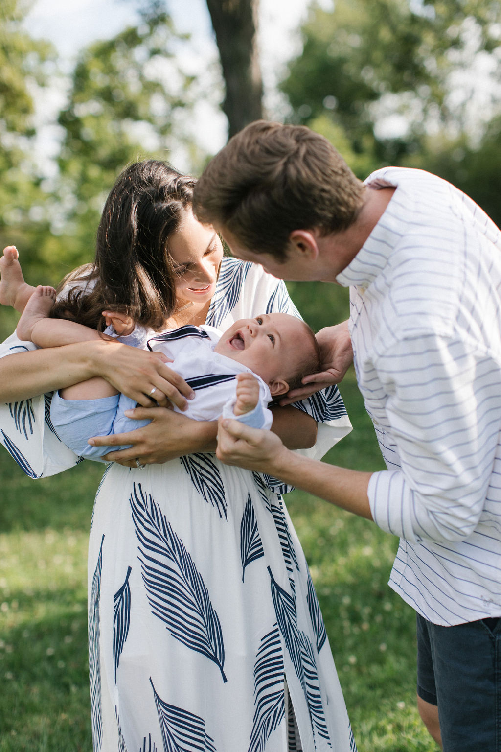 mom and dad playing a game with their baby boy during summertime family session 
