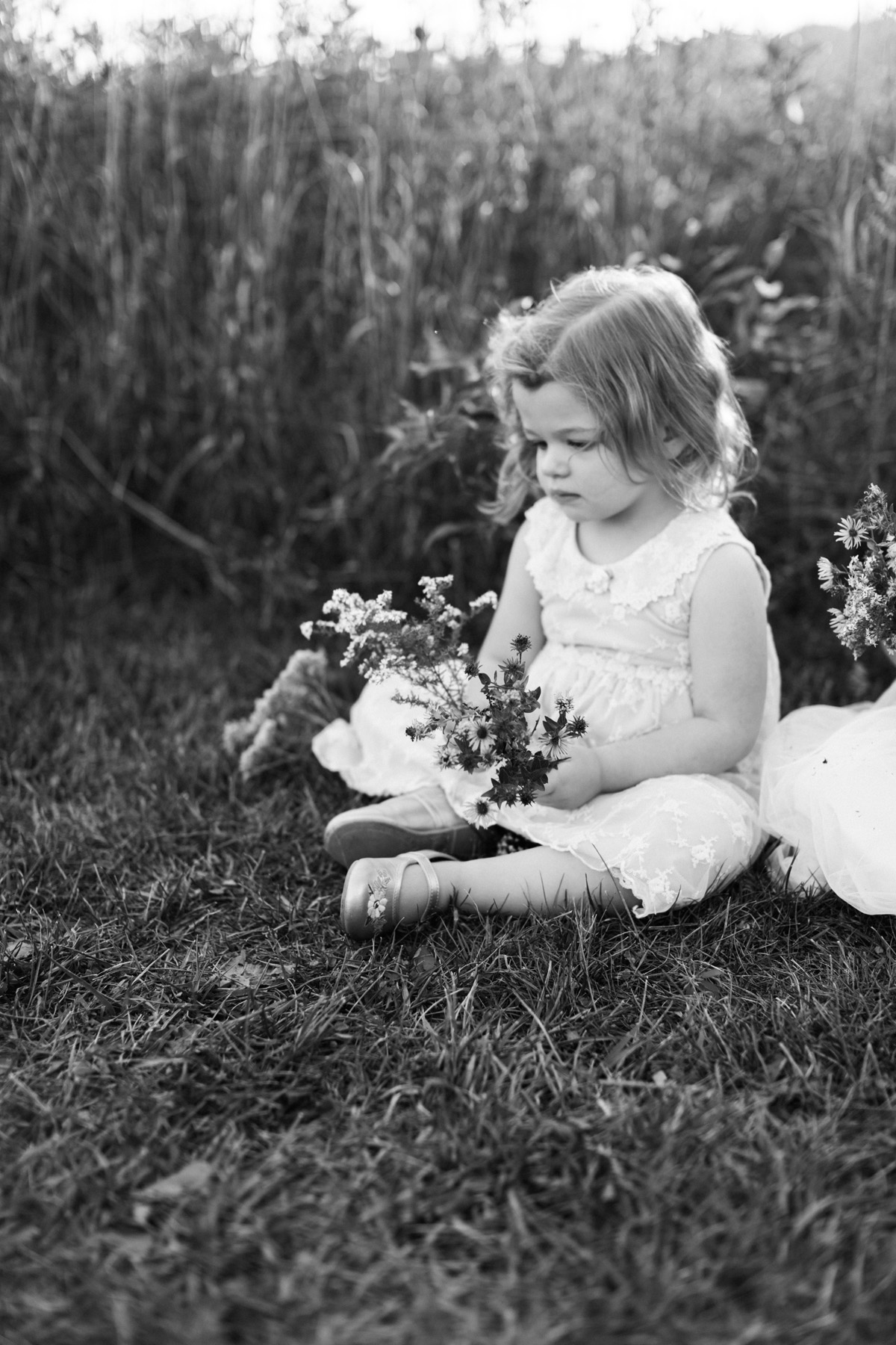 black and white image of a little girl looking at a large bouquet of flowers