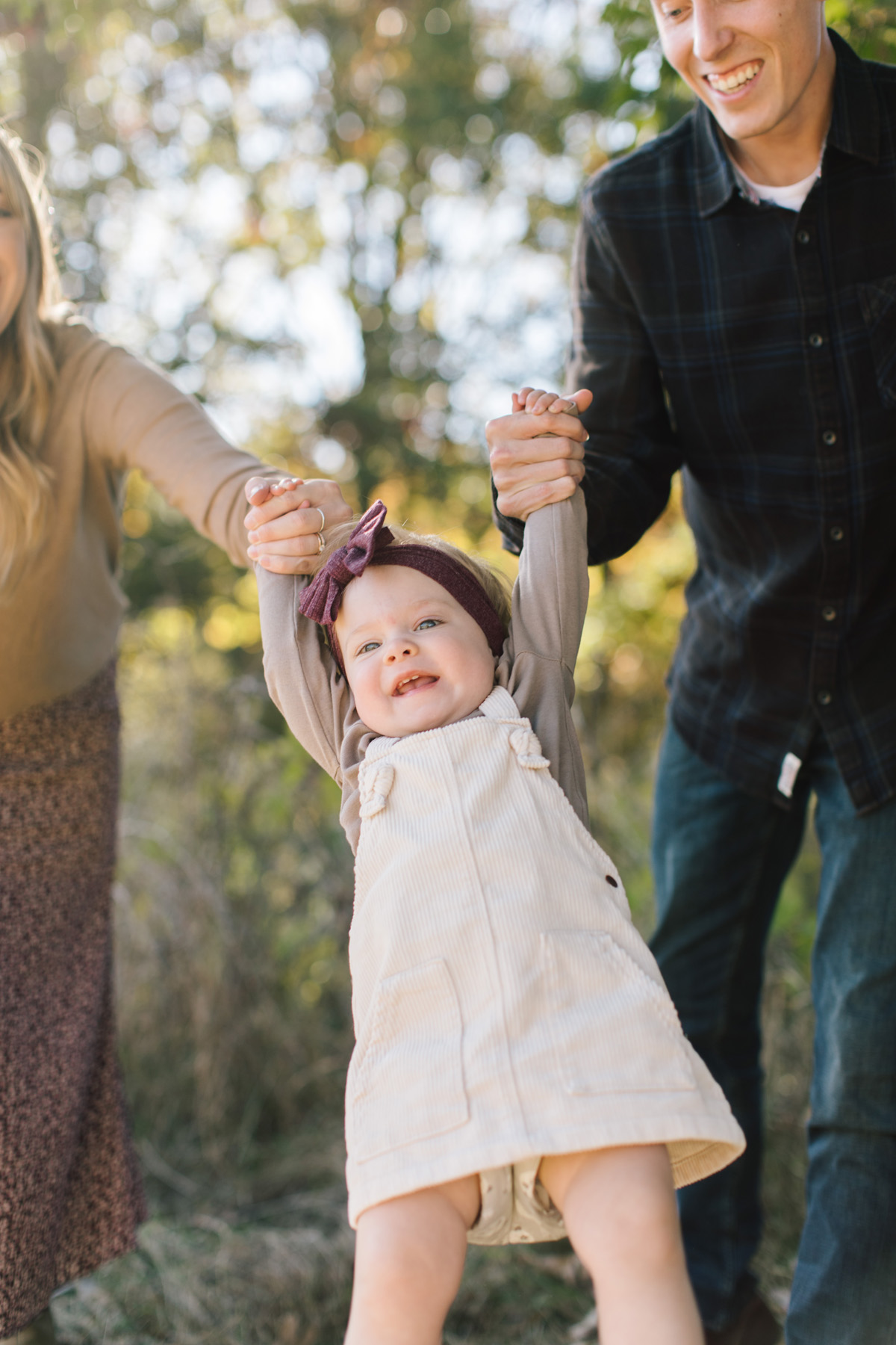 fall family mini session with adorable family of three swinging their daughter 