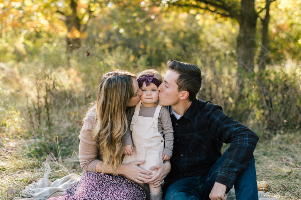 parents kissing their daughters cheeks during fall family mini session