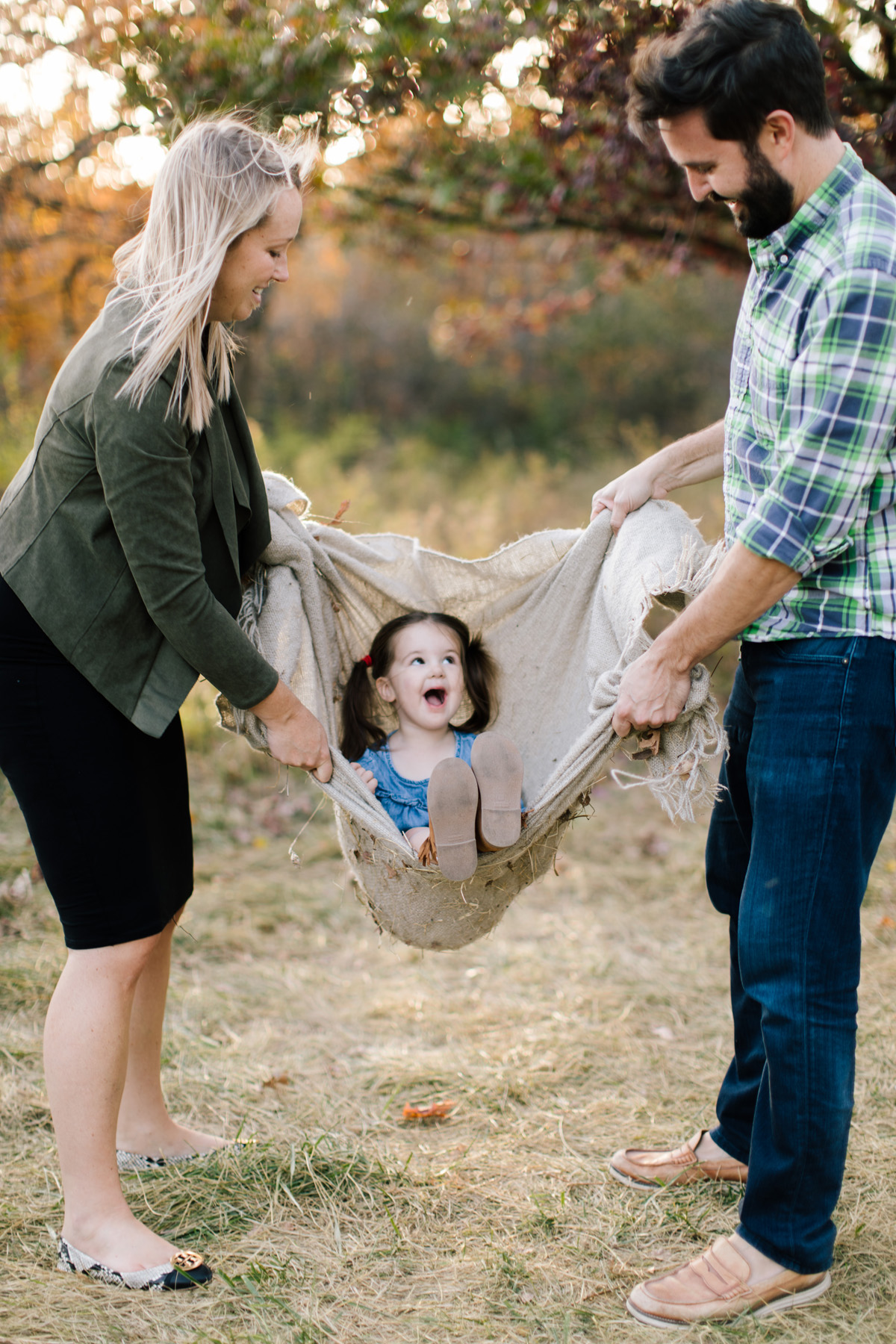 toddler in a blanket swing outside during family mini session 