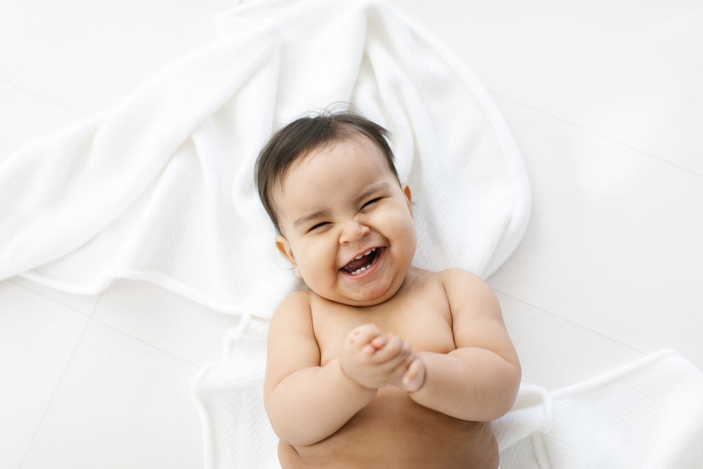 overhead photo of a baby with dark hair in a simple white room