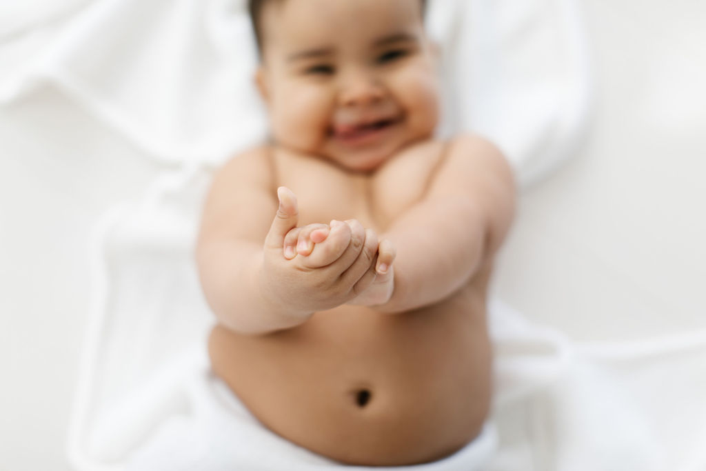 detail photo of a baby smiling and clapping her hands 