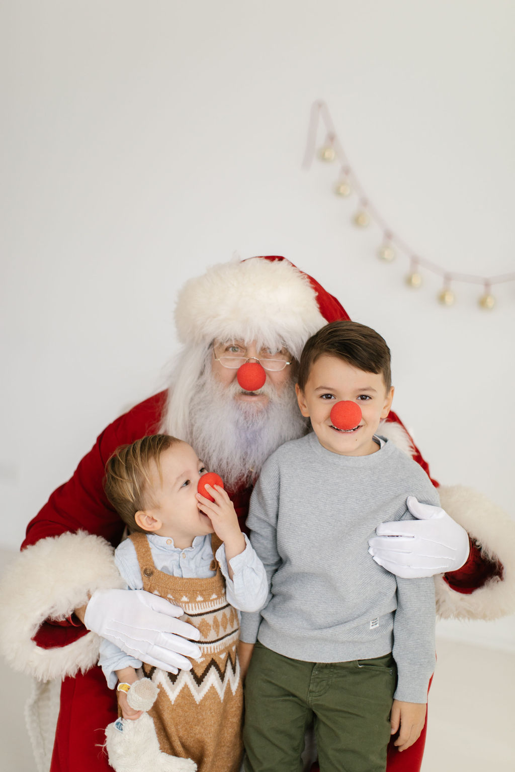 Santa playing with kids and dressing up as Rudolph during mini session