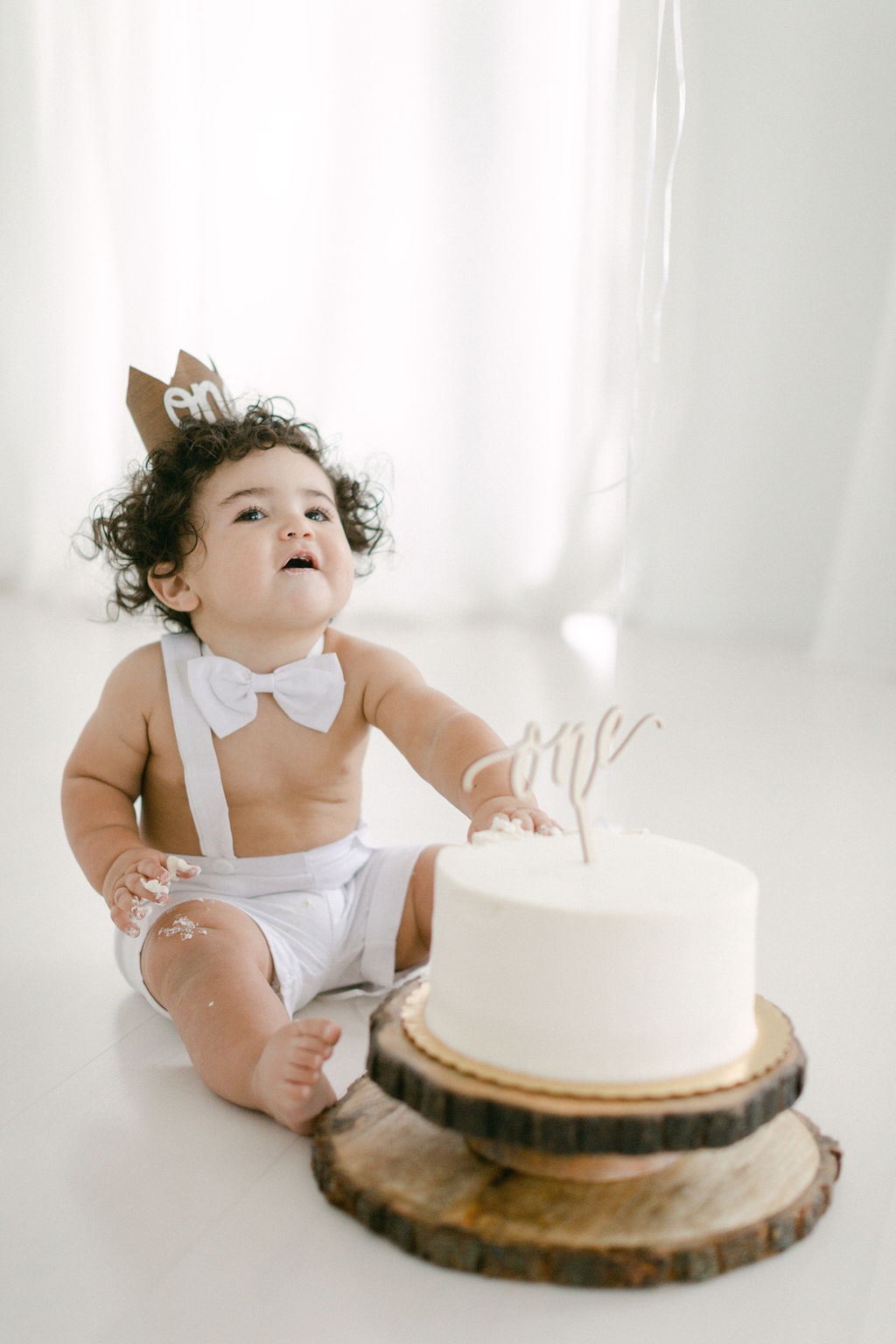 baby boy with brown curly hair and bow tie during first birthday session