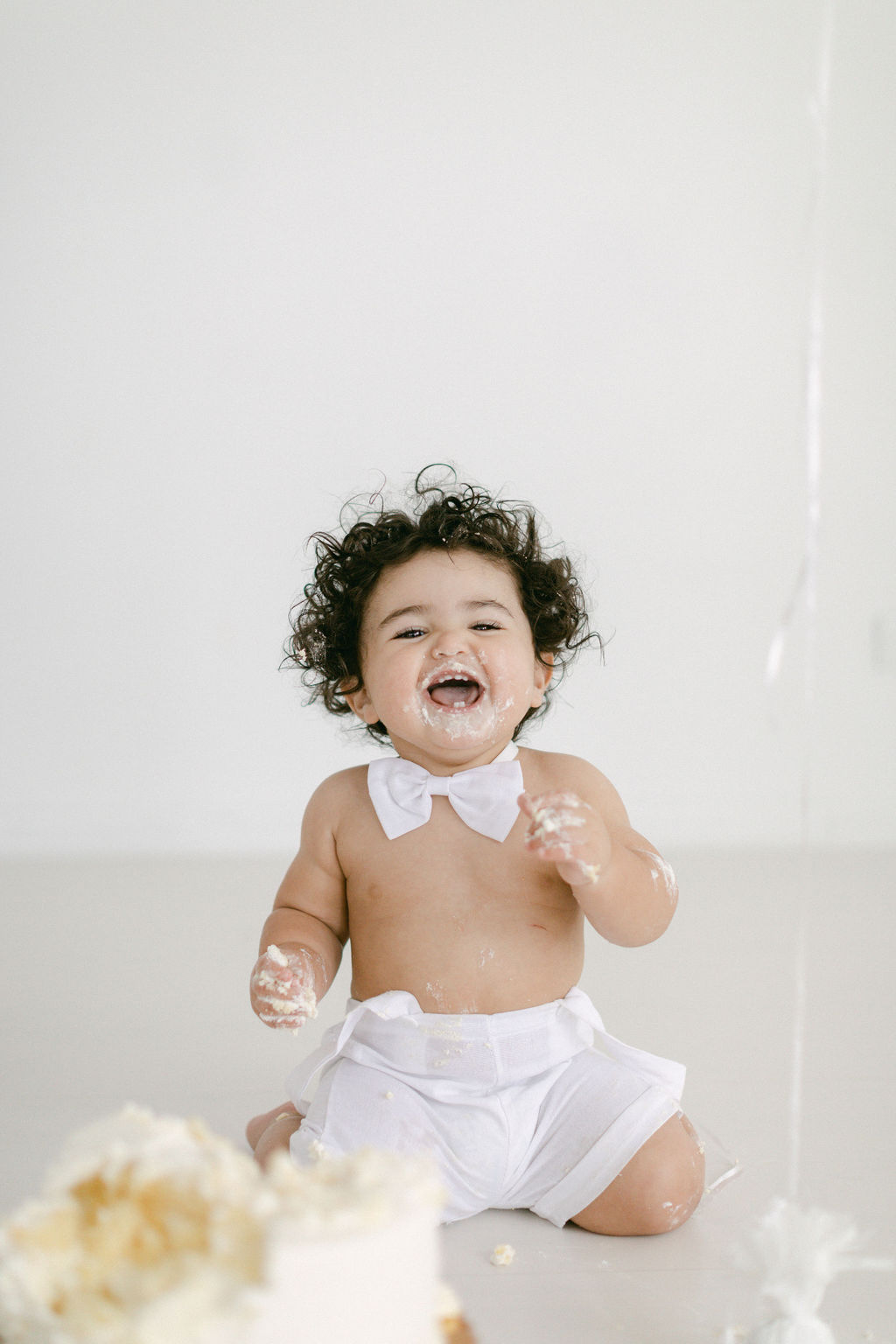 happy baby laughing during first birthday cake smash session